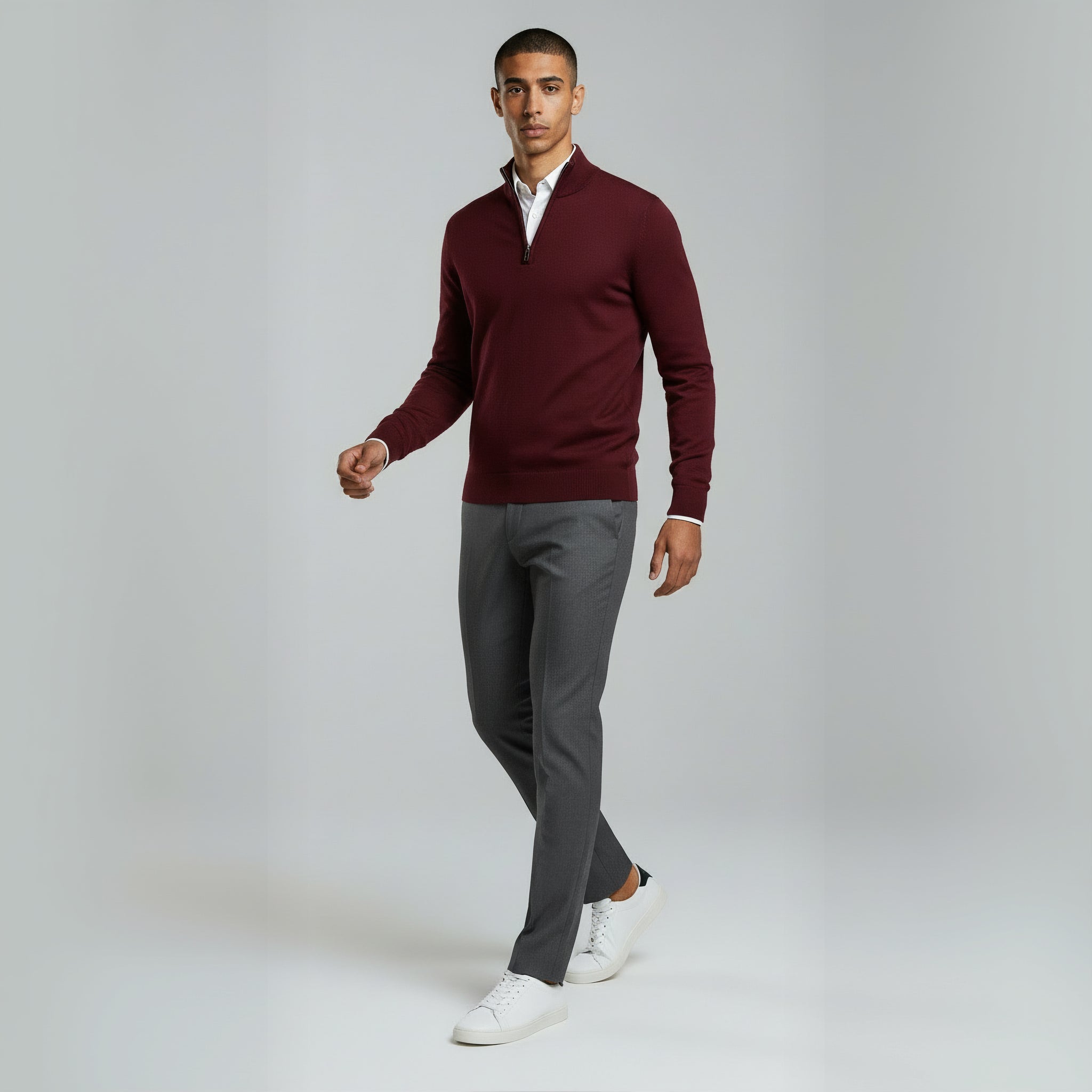man wearing maroon sweater and grey pants on a plain background