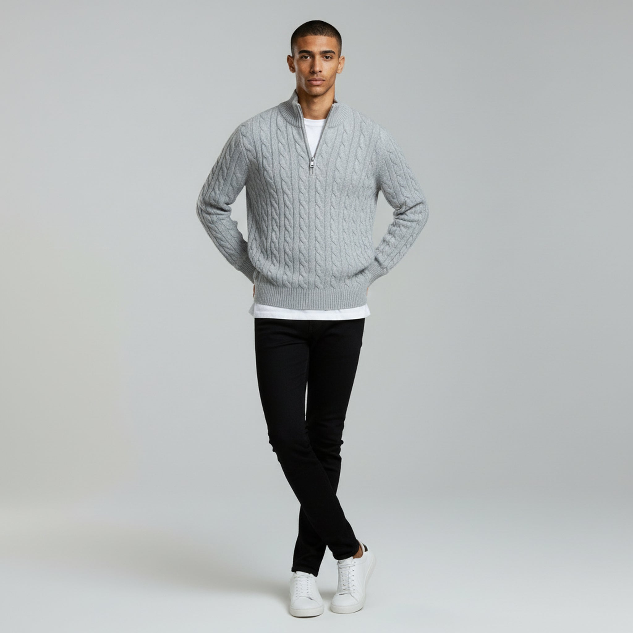 man wearing grey quarter zipped sweater and black pants on a plain background